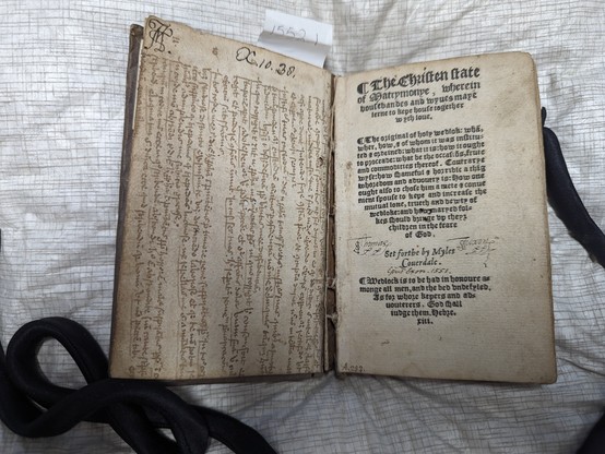 Book open at left endleaf that is manuscript waste rotated 90 degrees. Manuscript is iron gall ink.
Right page is the title page The Christen State of Matrymonye