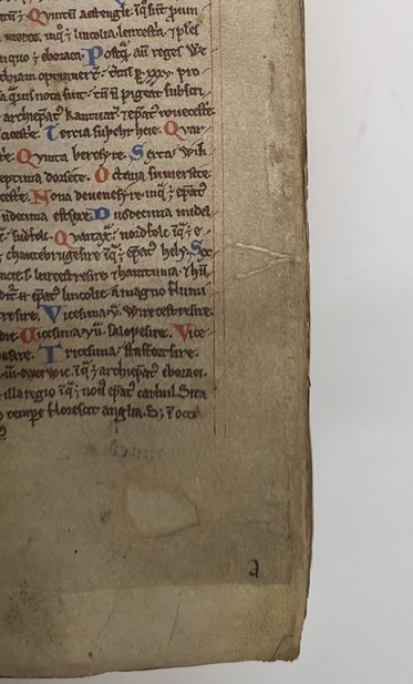 Parchment page with black manuscript. Red decorated letters. Beige thread attached in a v-shape. Thread twisted and projected from the foredges.